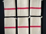 quatre serviettes blanches à rayures rouges sont posées sur une surface noire