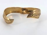 a close up of a gold bracelet on a white surface