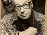 photographie en noir et blanc d'un homme portant des lunettes et une veste
