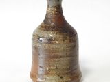 un petit vase brun posé sur une surface blanche