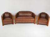 deux fauteuils en cuir marron et un canapé en cuir marron posés sur un sol blanc