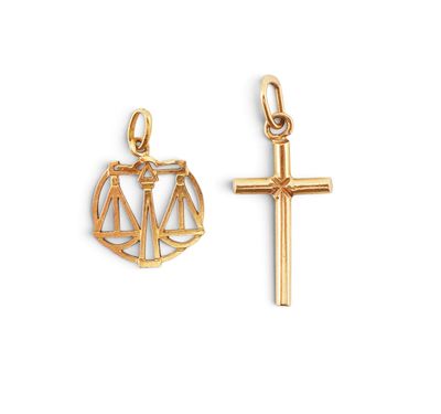 a gold charm with a cross and scales on it
