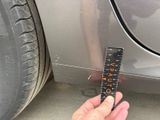 a hand holding a ruler that is on the side of a car
