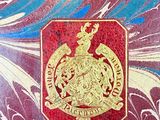 a close up of a red and blue book with a gold emblem on it