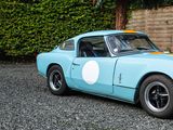 a blue and yellow sports car parked in front of a fence