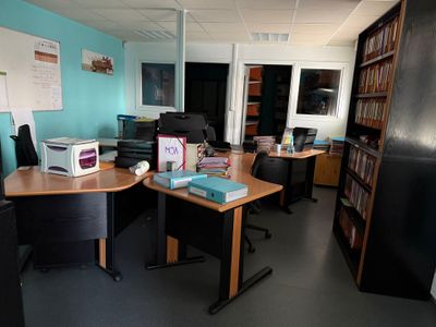 une pièce équipée d'un bureau, d'une chaise, d'une bibliothèque et d'un réfrigérateur