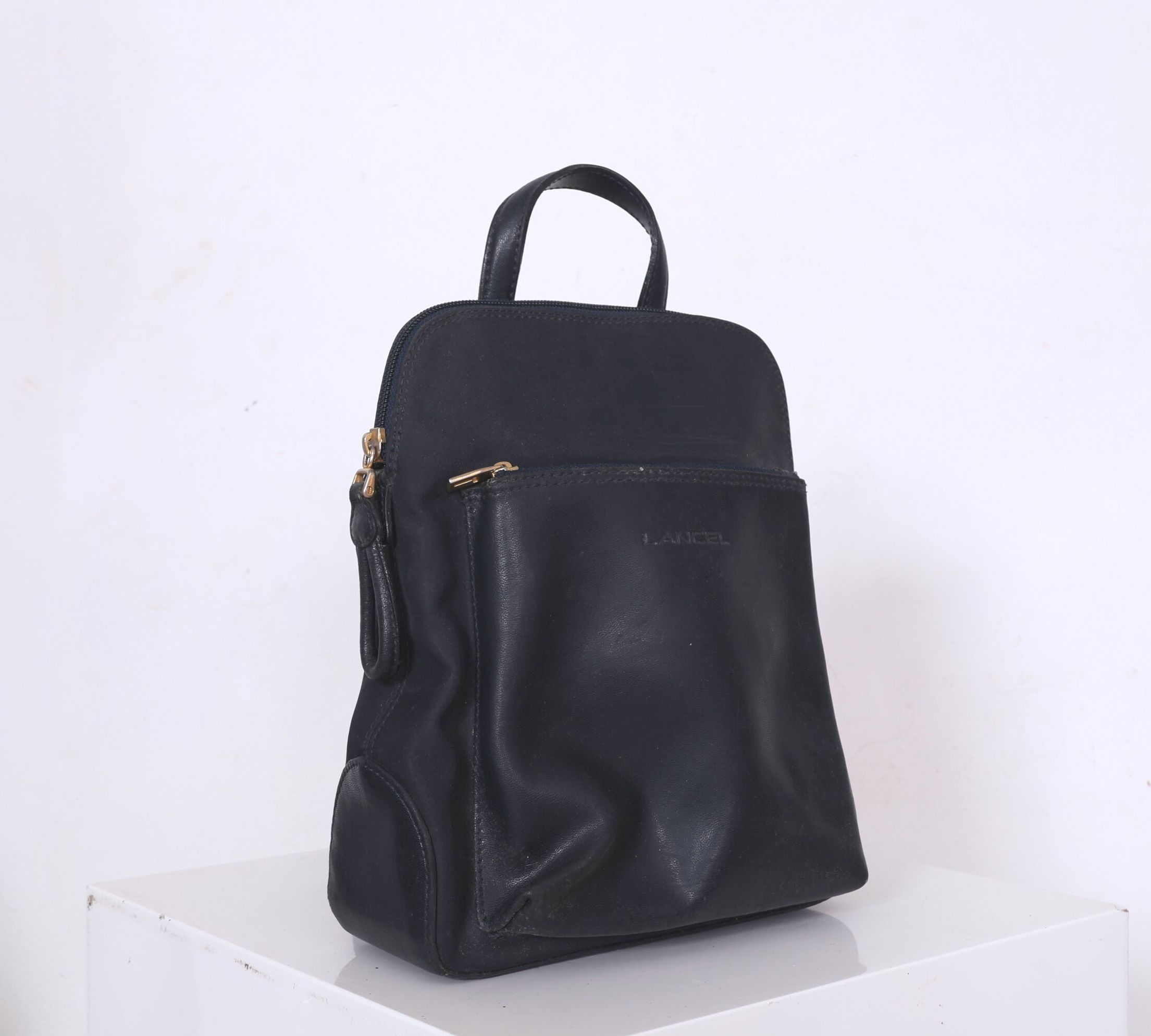 LANCEL, Paris. Petit sac à dos en cuir noir, pochette à l'avant, ouvertures à glissière. H_28 cm L_25 cm Légères usur...