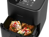 une friteuse à air chaud noire contenant des pizzas, sur fond blanc