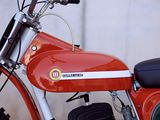 a red motorcycle parked next to a white wall