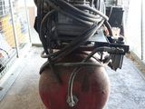 a red air compressor sitting on a stand in a garage