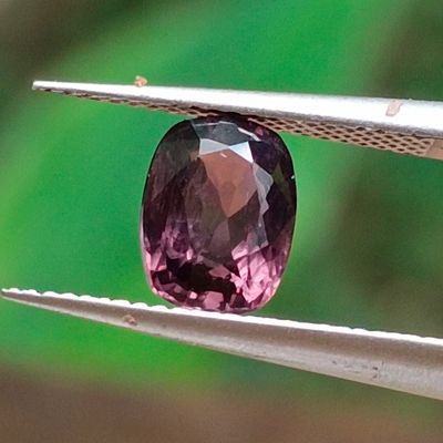 un gros plan d'une pierre précieuse violette tenue par une paire de pinces