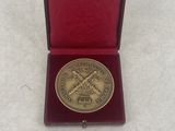 an image of a gold medal in a red box on a white surface