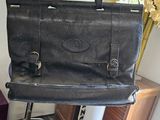 un sac noir posé sur un tabouret, à côté d'un vase de fleurs