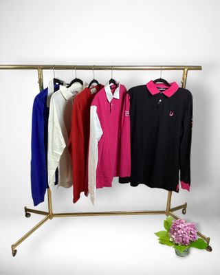 three shirts hanging on a clothes rack with flowers in front of them