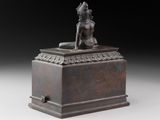 a bronze statue of a woman sitting on top of a box