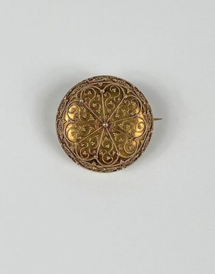 gros plan d'une broche en or sur une surface blanche