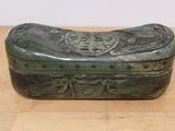 a green box sitting on a wooden table with a white wall behind it
