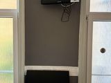 une petite table sur laquelle est posée une télécommande, devant deux fenêtres