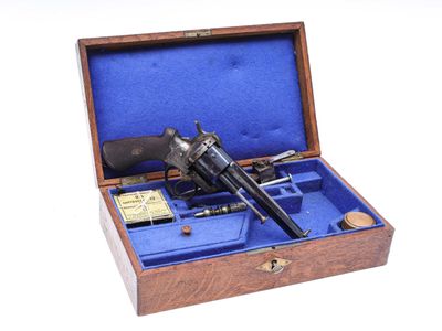 une boîte en bois contenant un pistolet, posée sur une surface blanche