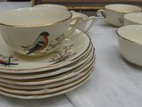 many cups and saucers on a table with a picture in the background