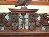 a large bird on top of a carved wooden cabinet
