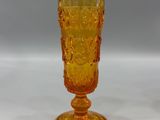 yellow glass goblet sitting on a white surface with a gray background