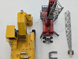 a red crane and a yellow construction vehicle on a white surface