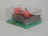un tracteur miniature dans une boîte transparente posée sur un socle vert