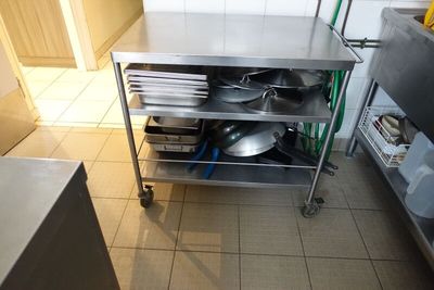 un chariot de cuisine en acier inoxydable sur lequel sont posés des casseroles et des poêles