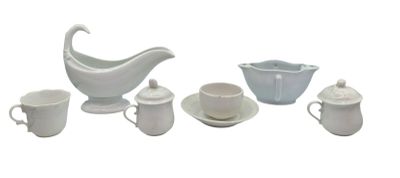 un pichet blanc, des tasses et des soucoupes posés sur une table blanche