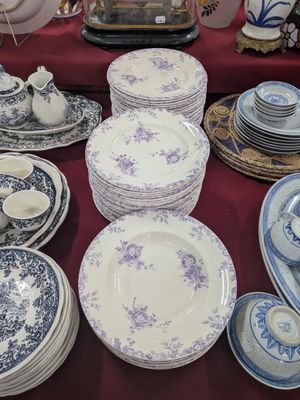 de nombreuses assiettes et bols posés sur une table, avec une horloge en arrière-plan