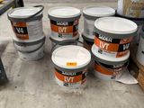 plusieurs seaux de peinture posés sur une palette dans un entrepôt