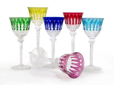 several different colored wine glasses sitting next to each other on a white surface