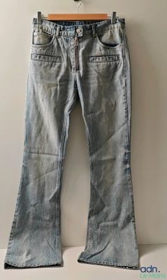 un pantalon en jean suspendu à un cintre devant un mur blanc