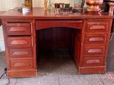 a wooden desk with drawers and a lamp on it