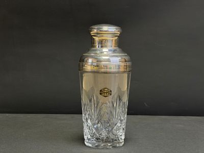 une photo d'un shaker à cocktail en argent et en verre posé sur une table