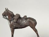 bronze statue of a horse with a saddle on a wooden base