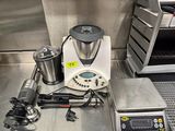 un plan de travail en acier inoxydable équipé d'un mixeur, d'une cafetière et d'autres appareils de cuisine