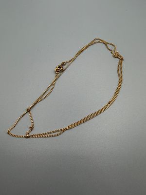 un gros plan d'un collier en or avec une chaîne posé sur une table