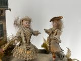 two dolls that are sitting on top of a rock