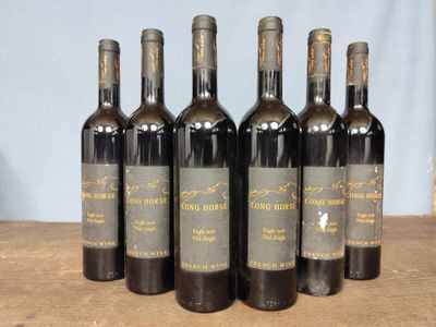 six bottles of wine are lined up on a wooden table