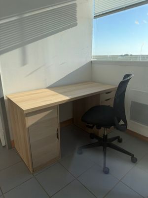 a computer desk with a chair in front of a window