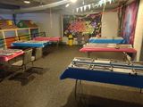 a room with many tables and chairs with colorful cloths on them