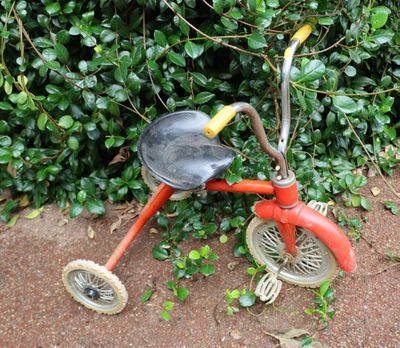 a red tricycle that is sitting on the ground