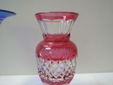 a pink glass vase sitting on a table next to a blue vase