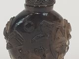 un vase marron muni d'un couvercle, posé sur une surface blanche