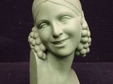 a green statue of a woman with a smile on it ' s face