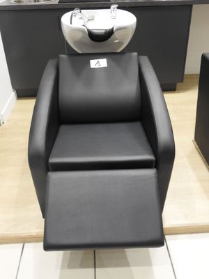 une chaise noire qui se trouve au milieu d'une pièce