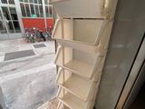 a stack of white shelves next to a refrigerator in a room