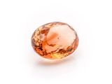a close up of an orange sapphire stone on a white surface